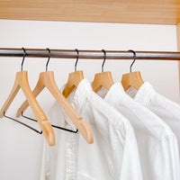 white shirts hung on a modern natural wooden hangers with black chrome non slip pant bar and black chrome 360 degree hook, minimalist capsule wardrobe design with natural hangers with black chrome hardware.