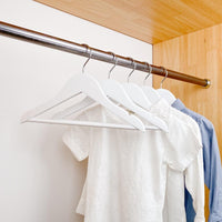 kids clothes hung on white kids wooden hangers, white shirt and blue shirt on children white wood hangers