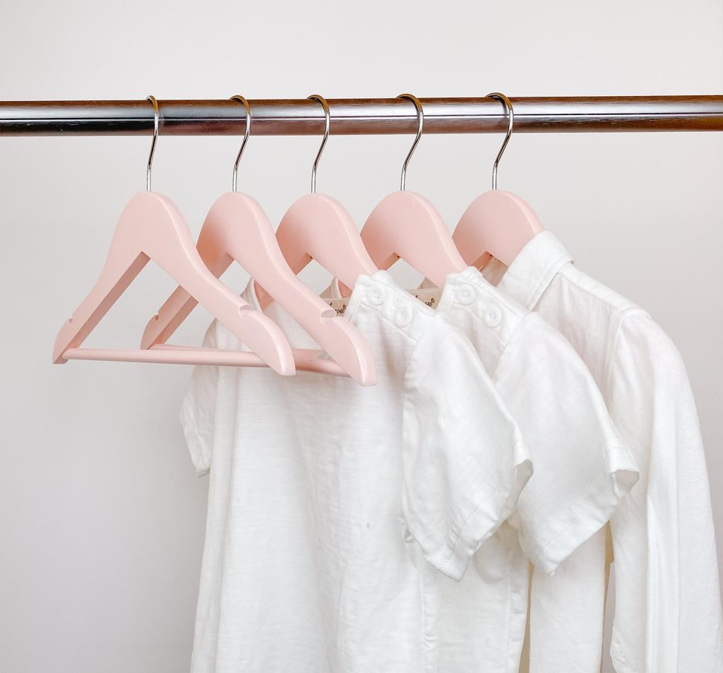 kids clothes hung on pink kids wooden hangers, white shirt and blue shirt on children pink wood hangers