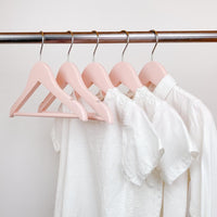 kids clothes hung on pink kids wooden hangers, white shirt and blue shirt on children pink wood hangers