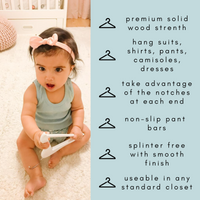 baby girl holding a kids wooden hanger, one year old child holding a wood hangers