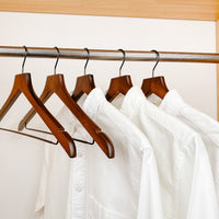 white shirts hung on a modern retro or dark brown wooden hangers with black chrome non slip pant bar and black chrome 360 degree hook, minimalist capsule wardrobe design with retro or dark brown hangers with black chrome hardware.