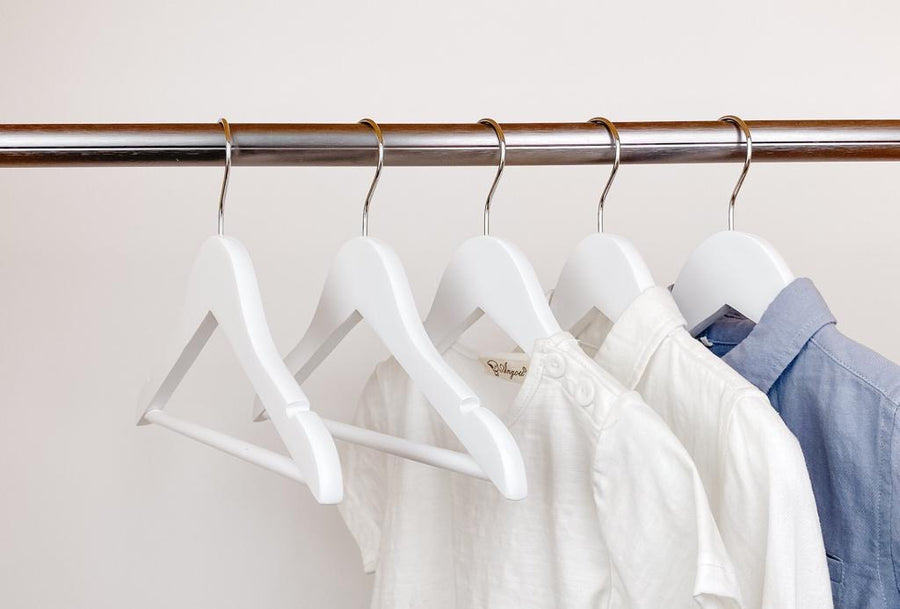 kids clothes hung on white kids wooden hangers, white shirt and blue shirt on children white wood hangers