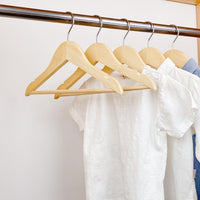 kids clothes hung on natural kids wooden hangers, white shirt and blue shirt on children natural wood hangers