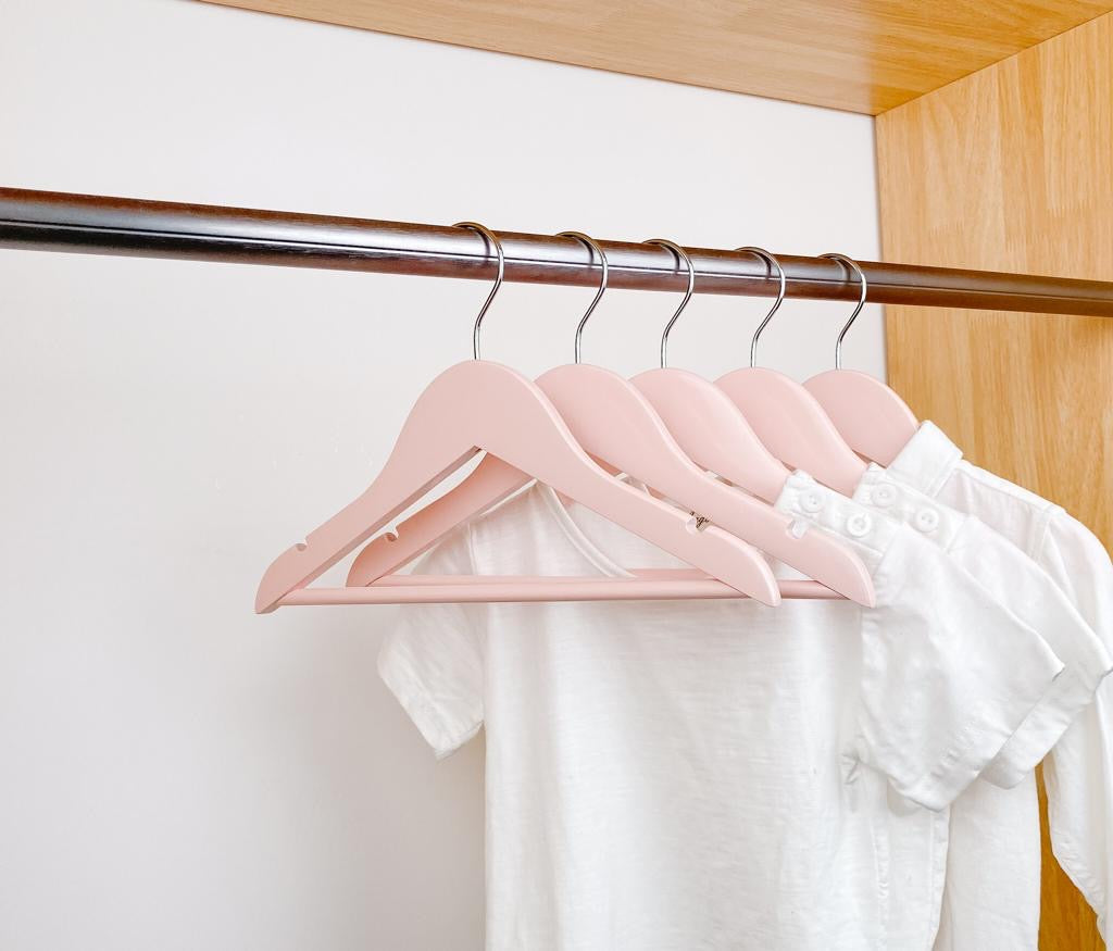 kids clothes hung on pink kids wooden hangers, white shirt and blue shirt on children pink wood hangers
