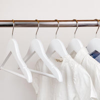 kids clothes hung on white kids wooden hangers, white shirt and blue shirt on children white wood hangers