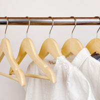 kids clothes hung on natural kids wooden hangers, white shirt and blue shirt on children natural wood hangers